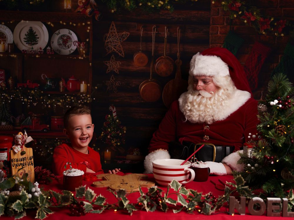 A festive Christmas scene with Santa Claus sitting in a cozy room decorated with holiday lights and greenery.