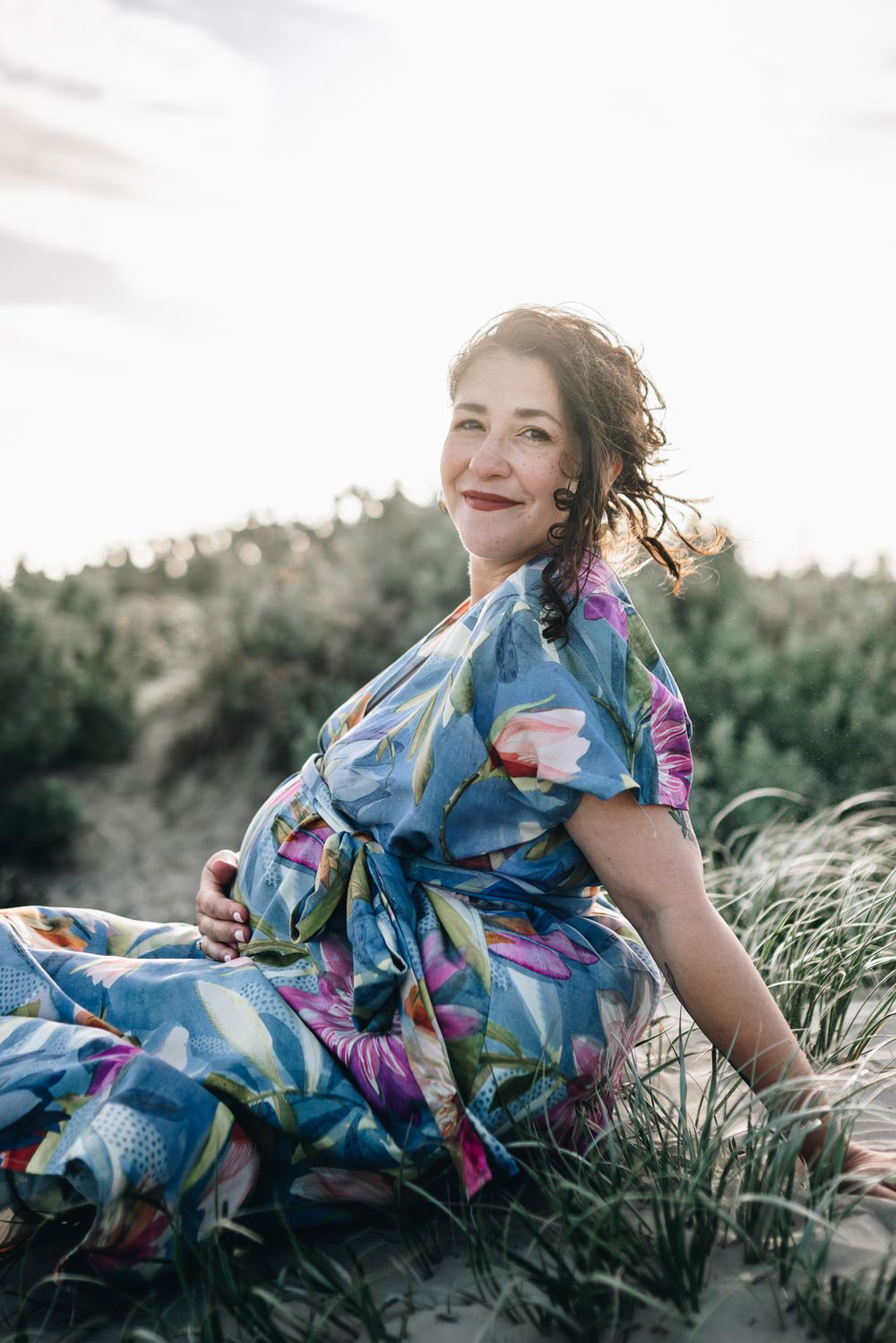 Portrait of a pregnant lady sitting by the beach with grassy field taken by a Melbourne maternity photographer.