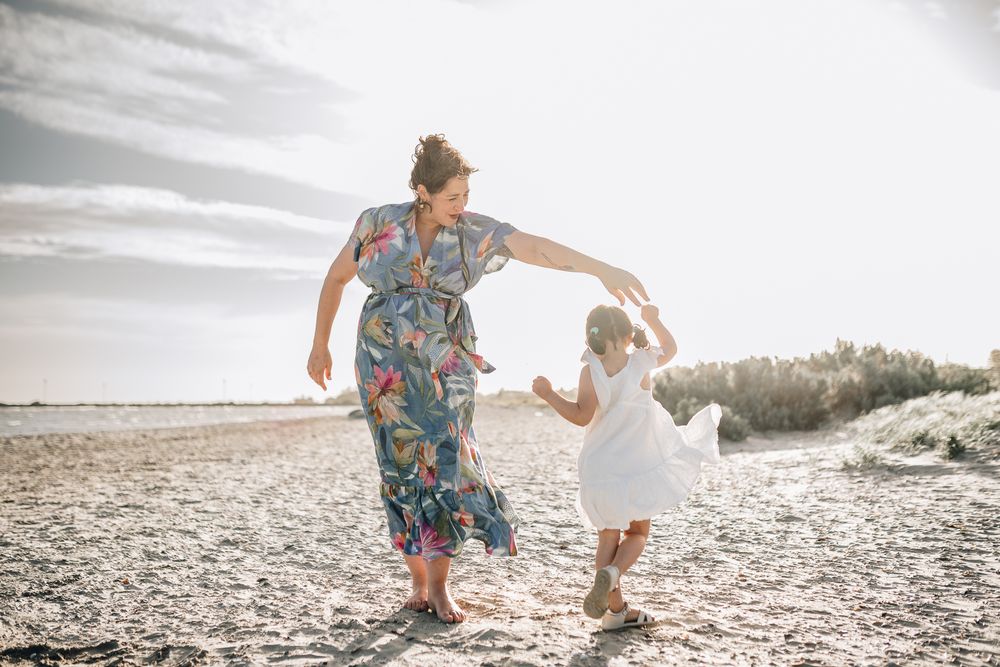 A pregnant lady twirling her toddler daughter by the beach during sunset taken by a Melbourne maternity photographer.