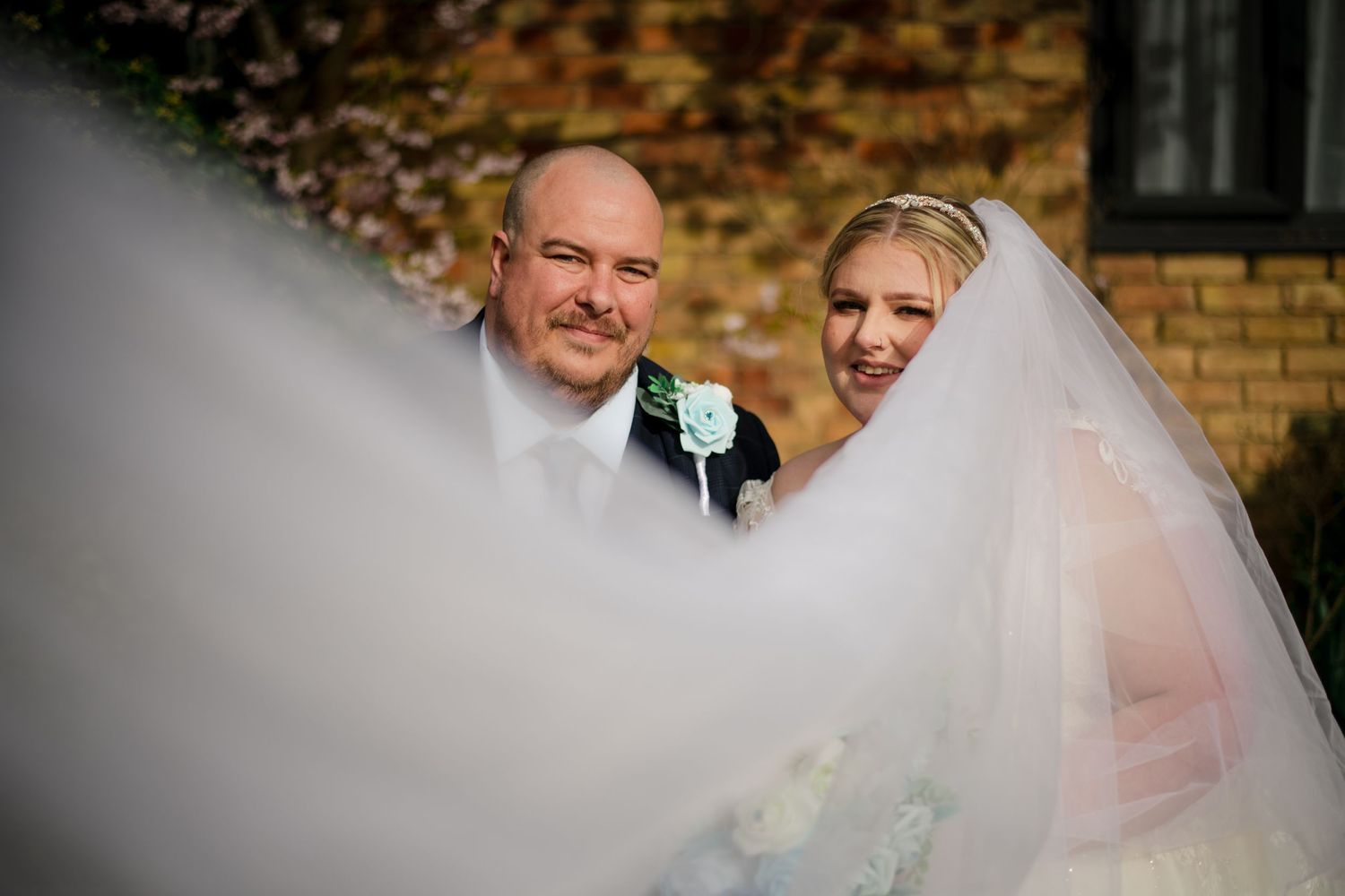A couple shares their first kiss as newlyweds outdoors on an overcast day during their wedding ceremony.