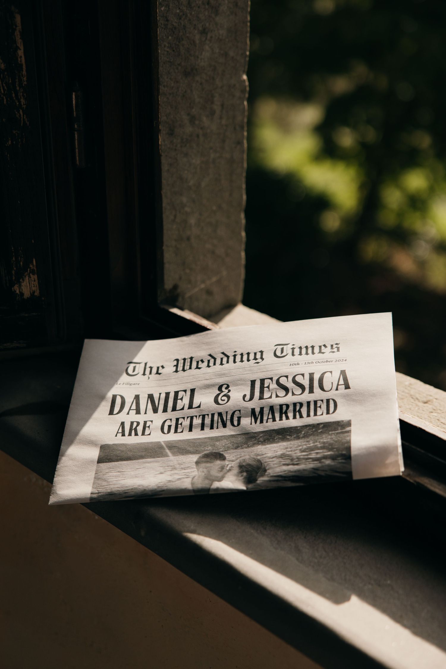 Wedding announcement newspaper clipping in dramatic window lighting.