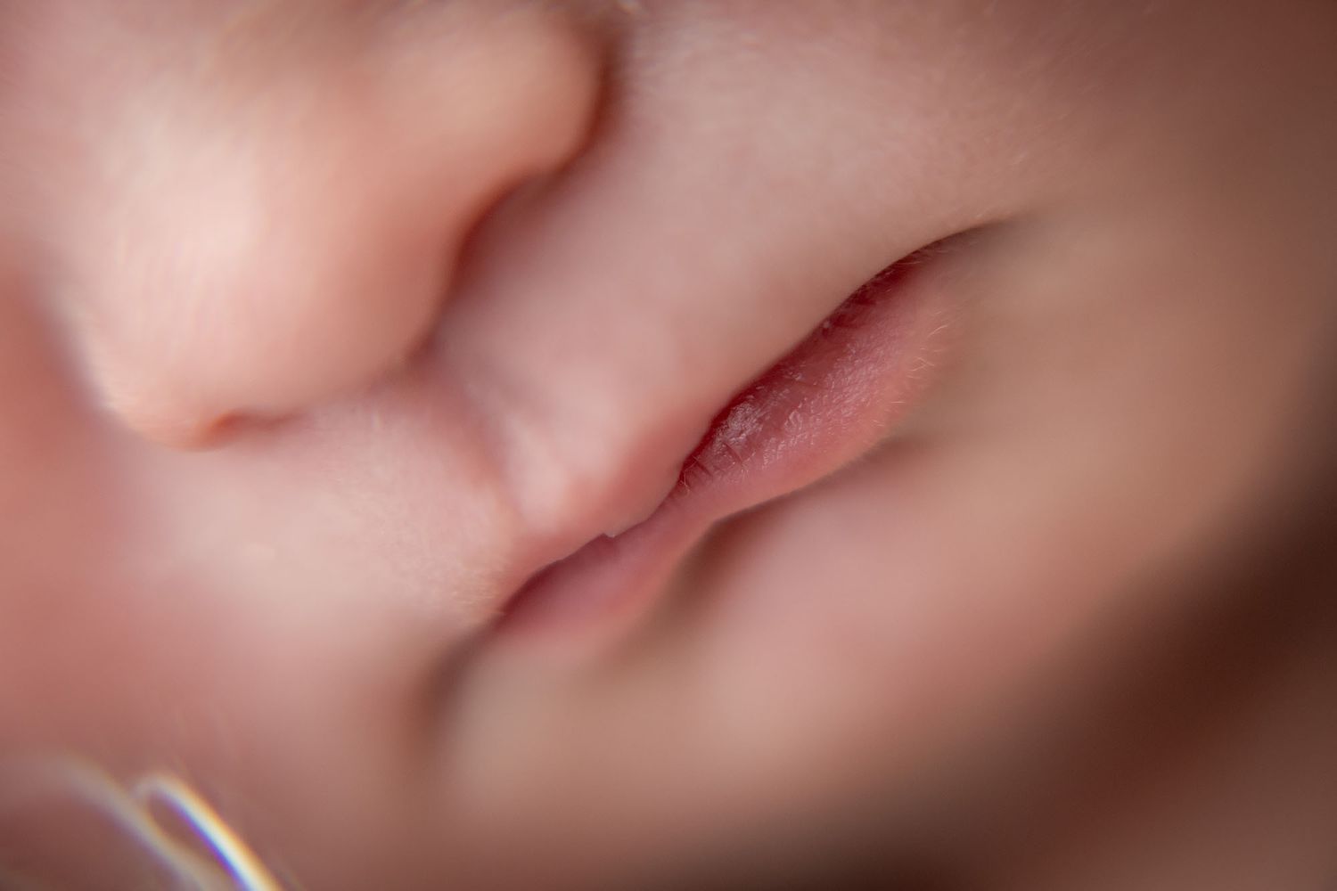 Extreme close-up macro shot of soft pink lips with shallow depth of field.