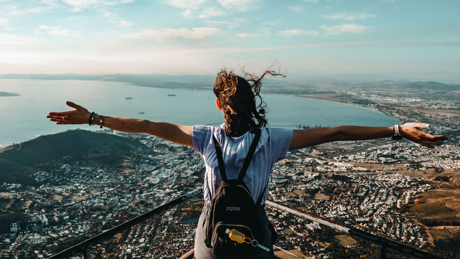 Aerial panorama of a coastal city with people gesturing against the expansive view.
