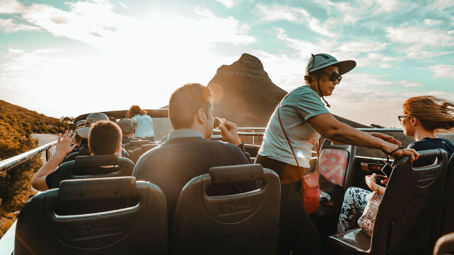 People enjoying a scenic coastal drive in convertible cars along mountain roads.