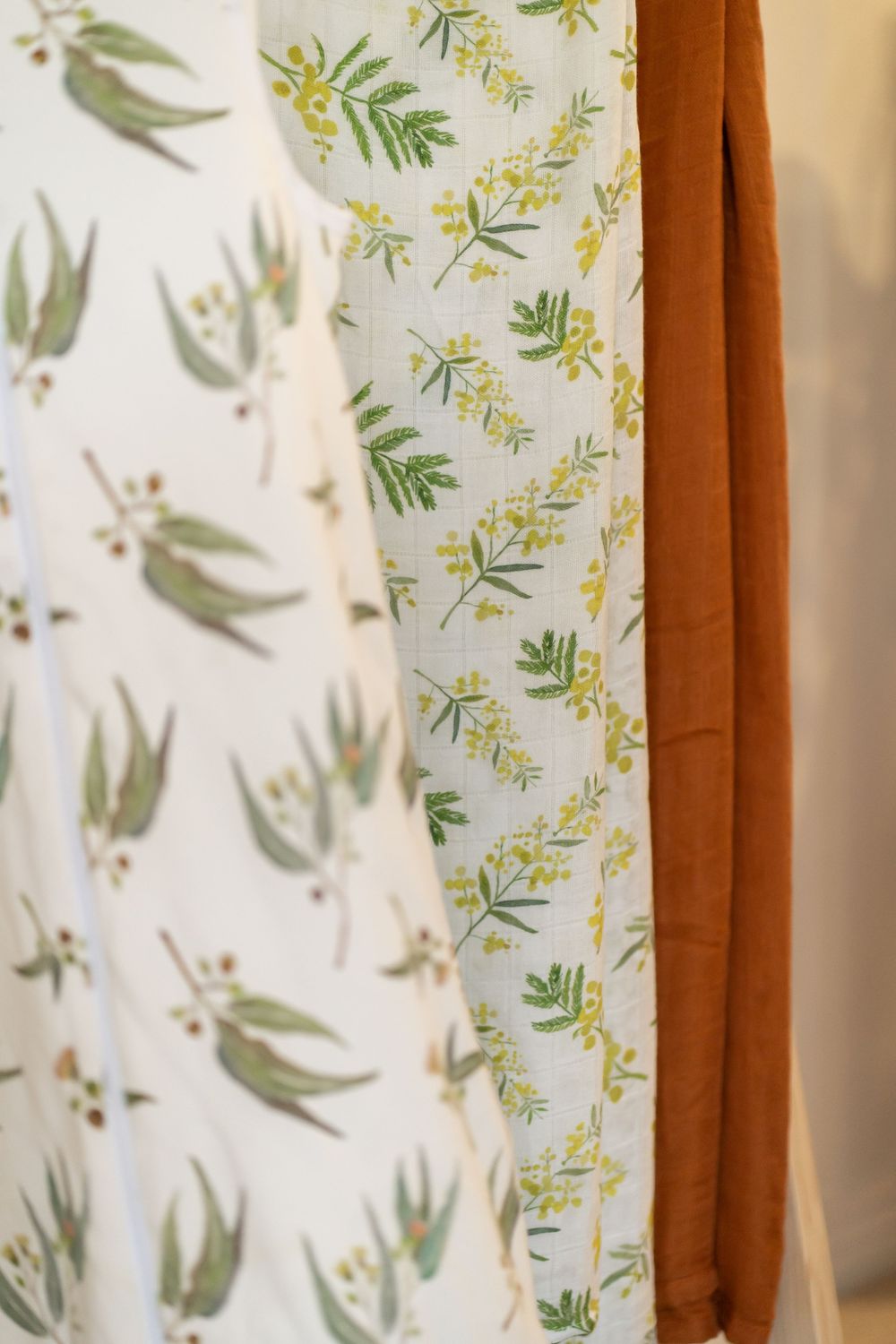 Decorative curtain fabric featuring delicate botanical print with green leaves and branches on white background.