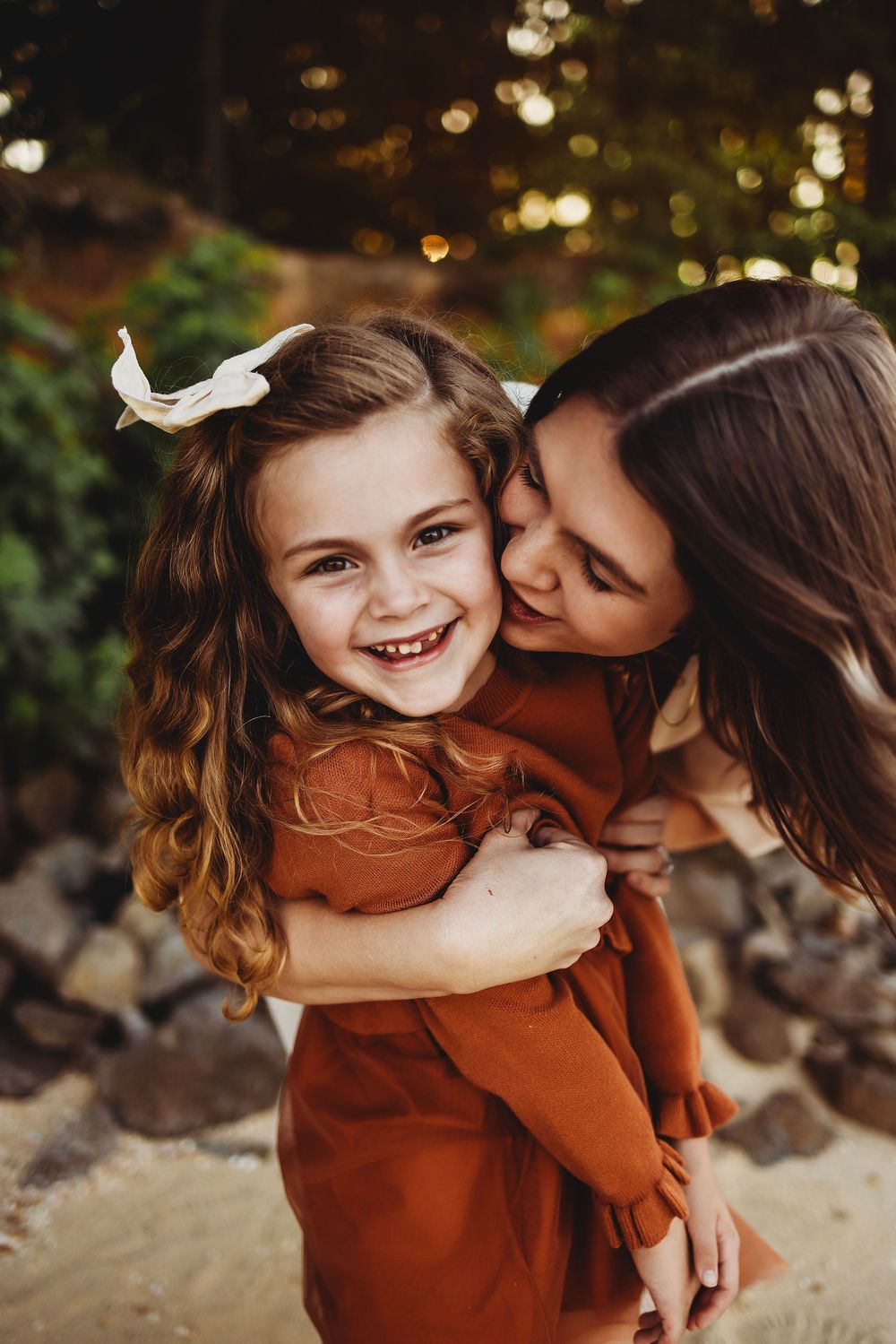 A heartwarming moment of affection and laughter captured outdoors with warm autumn tones and bokeh lighting effects.