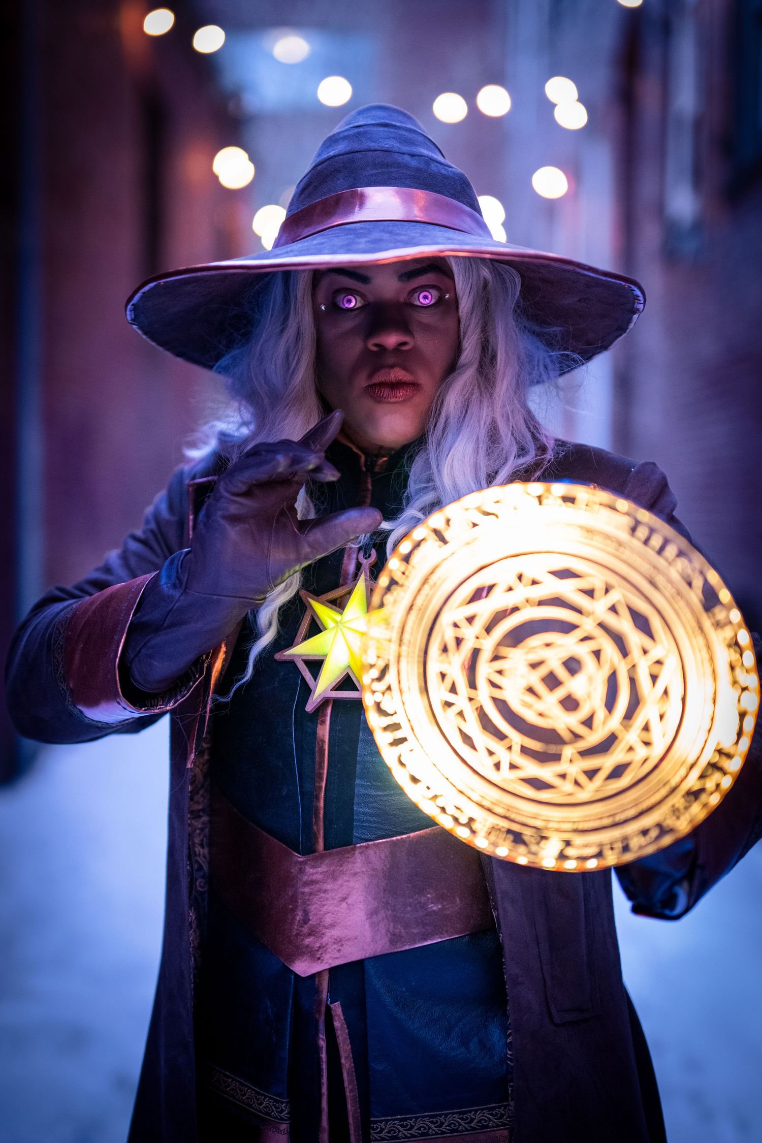 Performer in mystical costume holding illuminated magical circle prop with bokeh background.