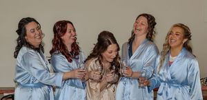 A group in matching blue silk robes laughing together joyfully during a celebratory moment.