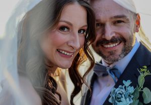 A romantic outdoor wedding portrait on a sunny day with floral accents.
