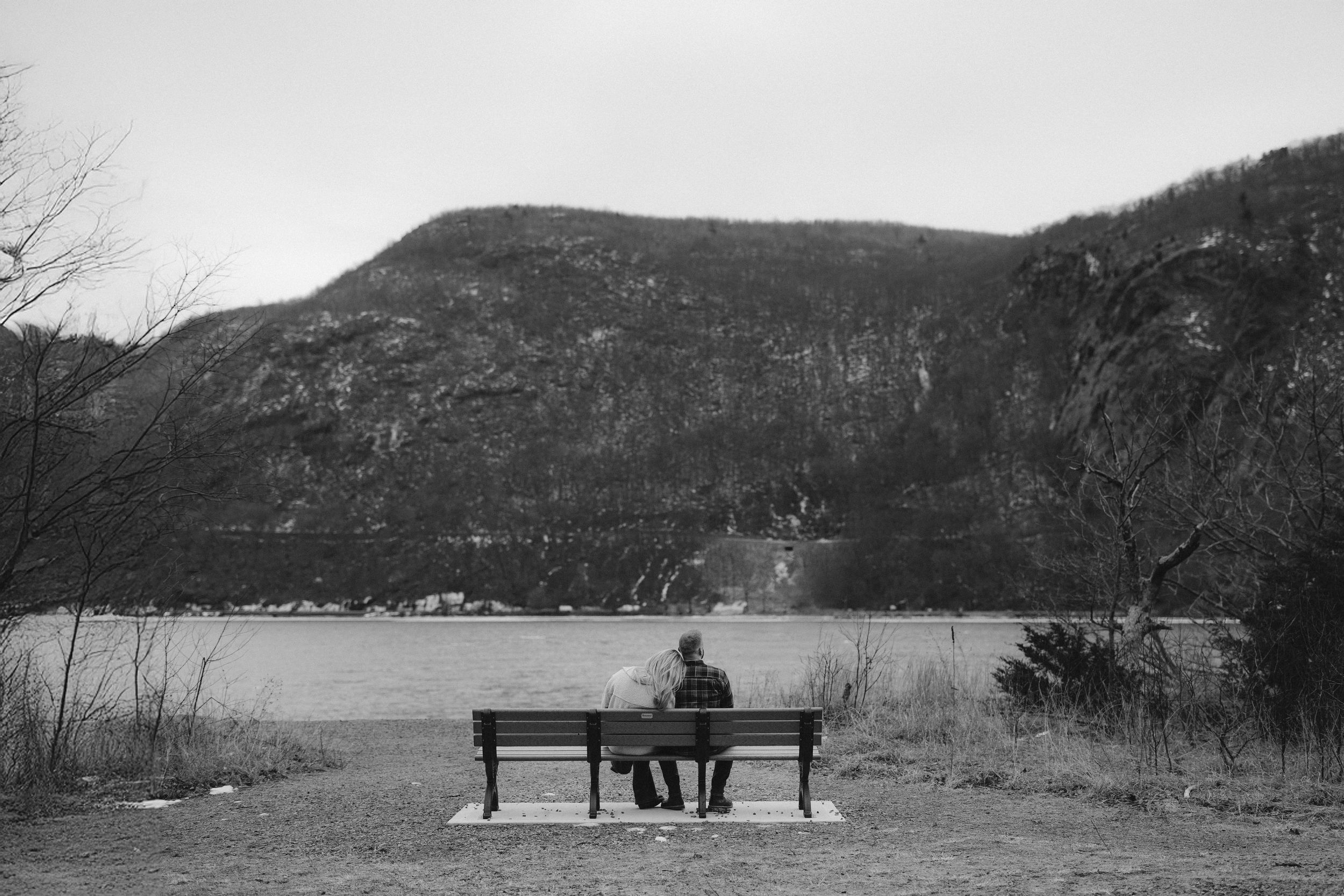 A series of black and white landscape photographs showing mountains, lakes, and people sitting on benches in nature.