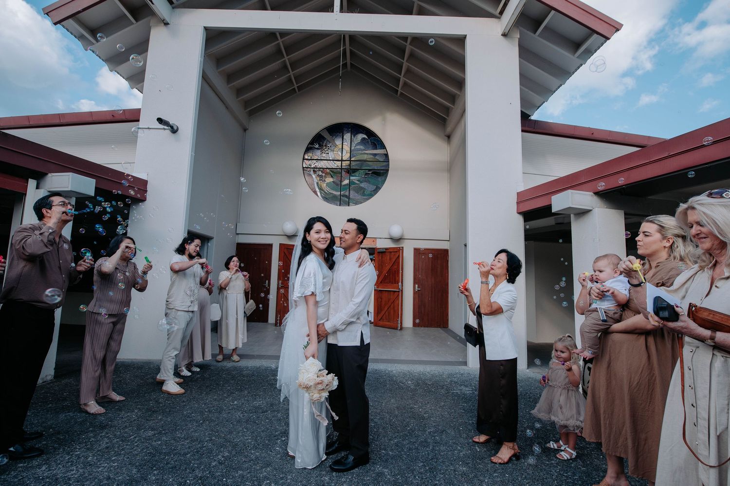 Celebratory moment outside a white church building with traditional architecture and gathered guests in formal attire.
