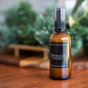 Amber glass spray bottle of Dawn & Co handmade product with black label on wooden surface.
