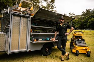 Professional landscaping service trailer showing organized equipment storage and yellow mower.
