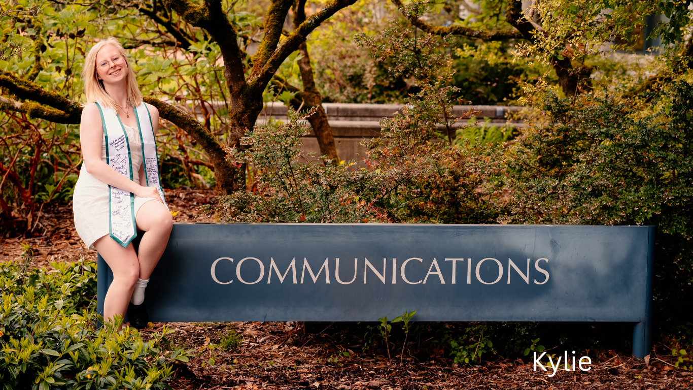Someone sitting on stone Communications sign surrounded by autumn foliage.