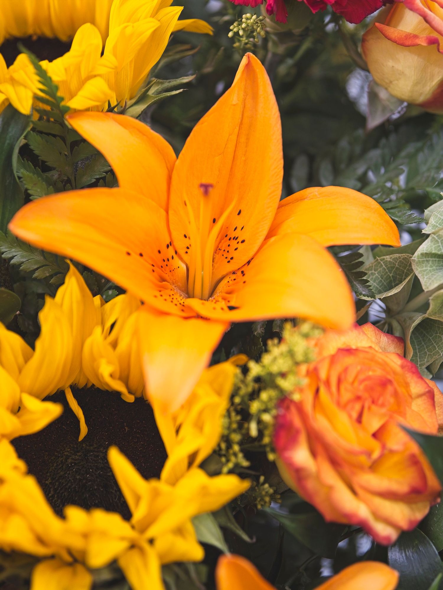 An orange flower arrangement with lilies and roses and other flowers