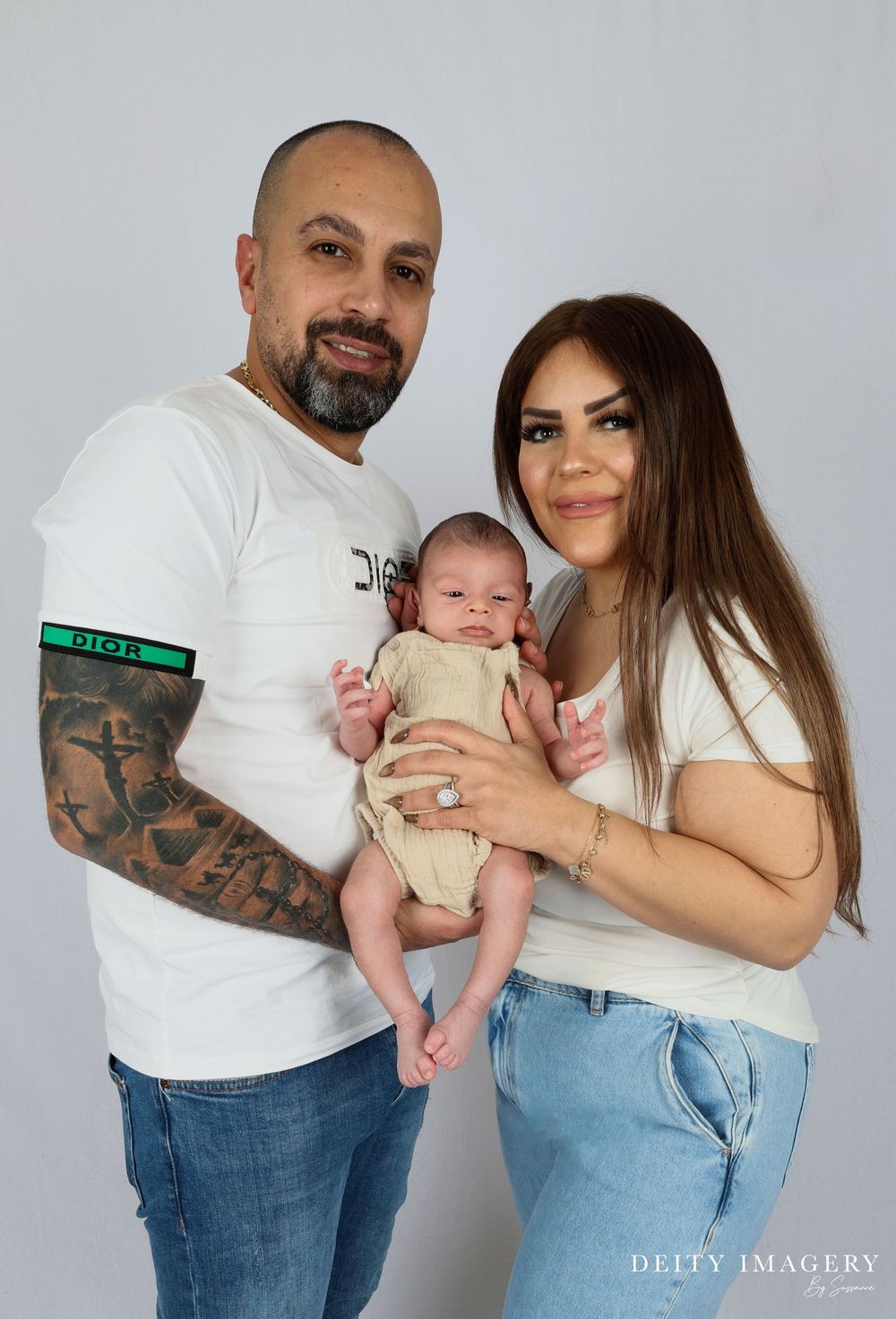Family portrait session showing multiple candid poses against a light gray studio backdrop in matching jeans and white shirts.