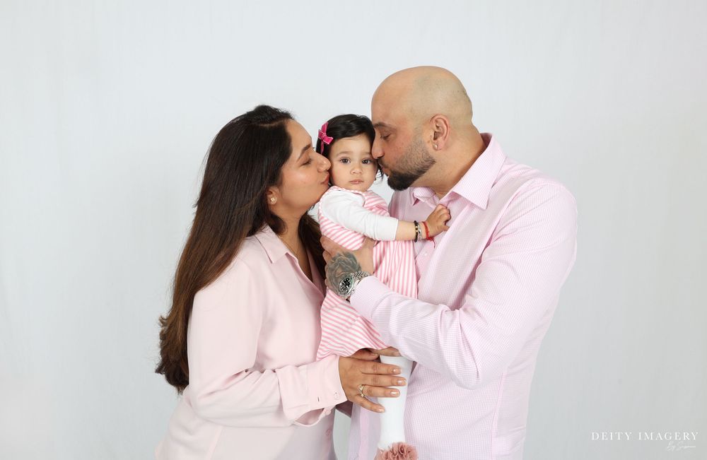 A couple in pink outfits poses for a romantic photoshoot with their baby in multiple tender moments.