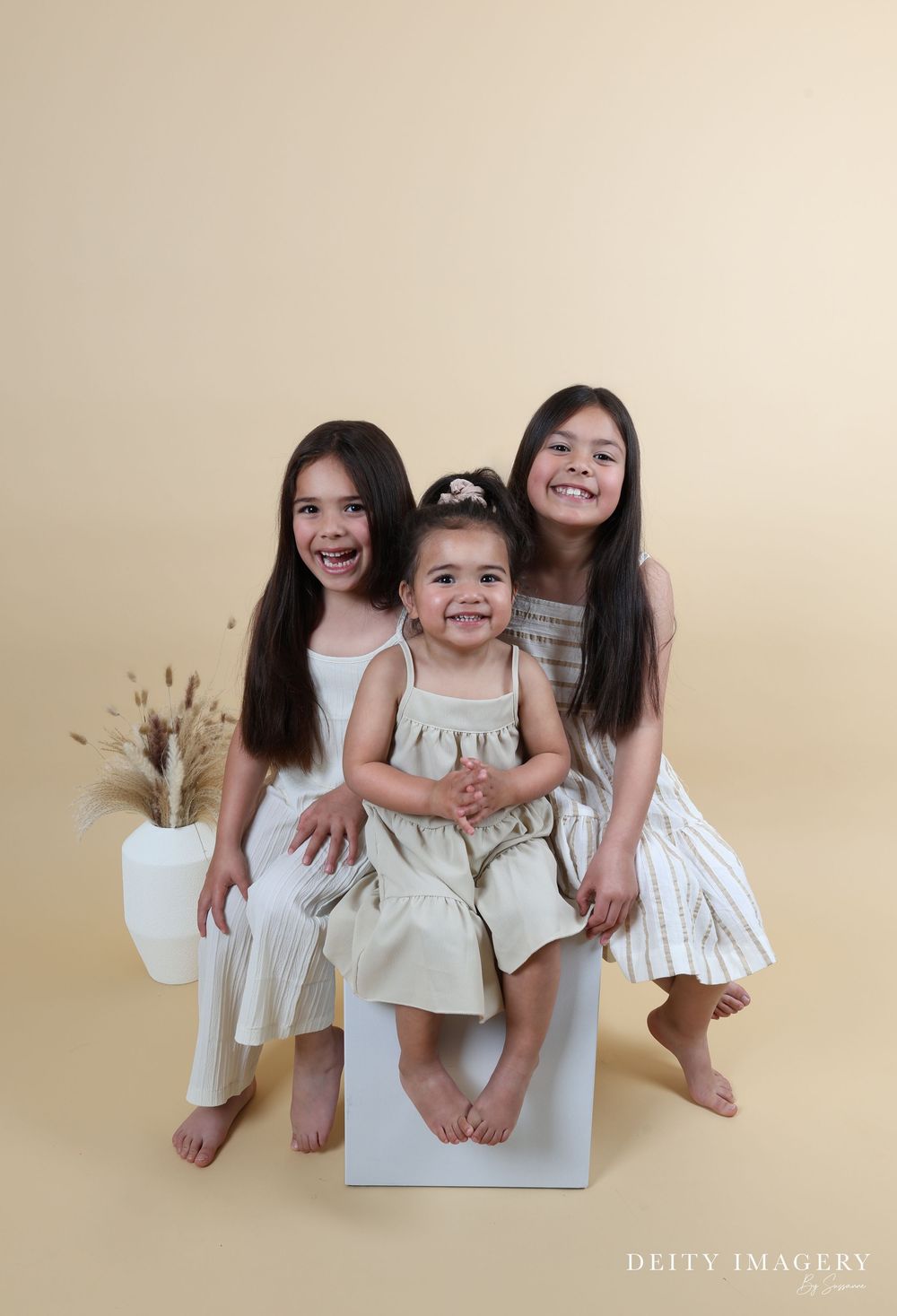 A series of candid family photos showing people in white outfits sitting and posing playfully against a beige backdrop.