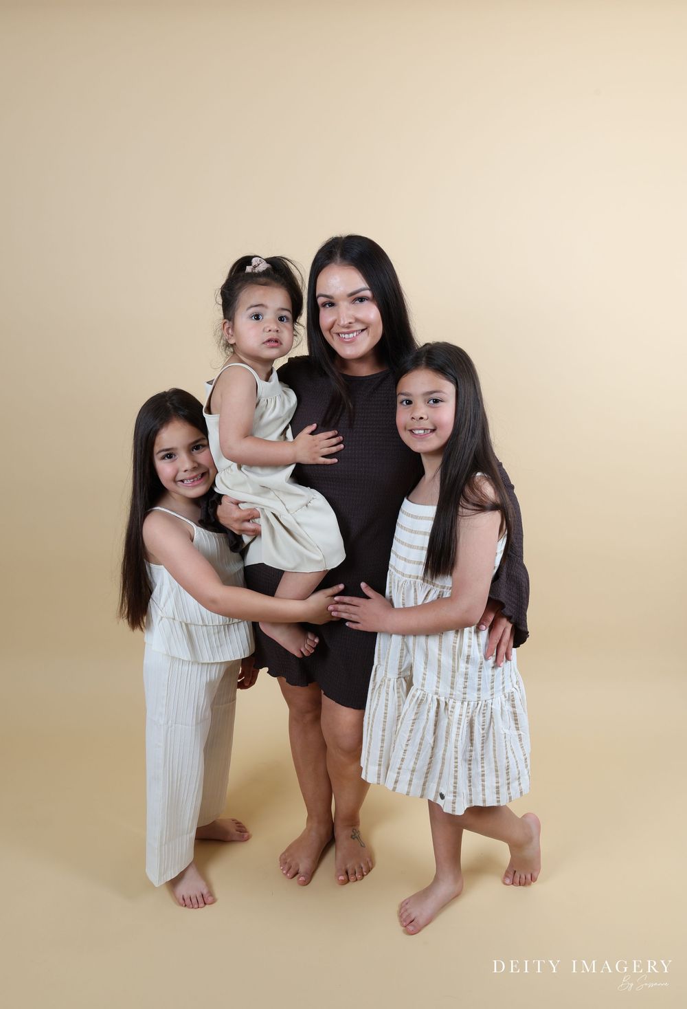 Four heartwarming family photos show a mother and children posing together on a beige backdrop in coordinating white outfits.