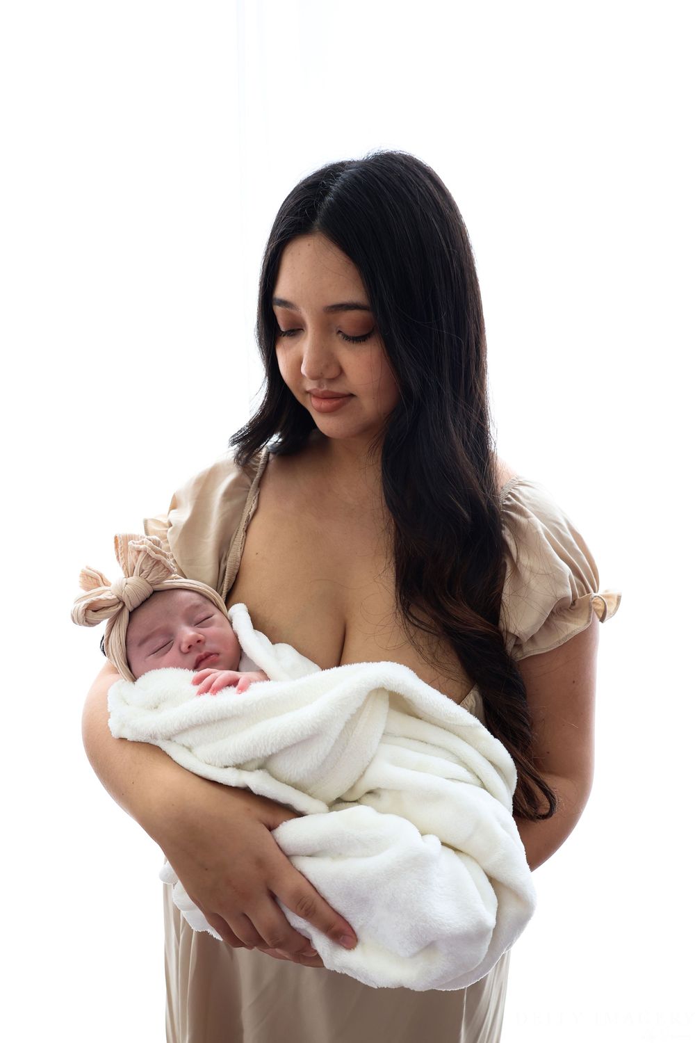 A person in a white dress holds a newborn baby wrapped in a soft white blanket in three similar poses.