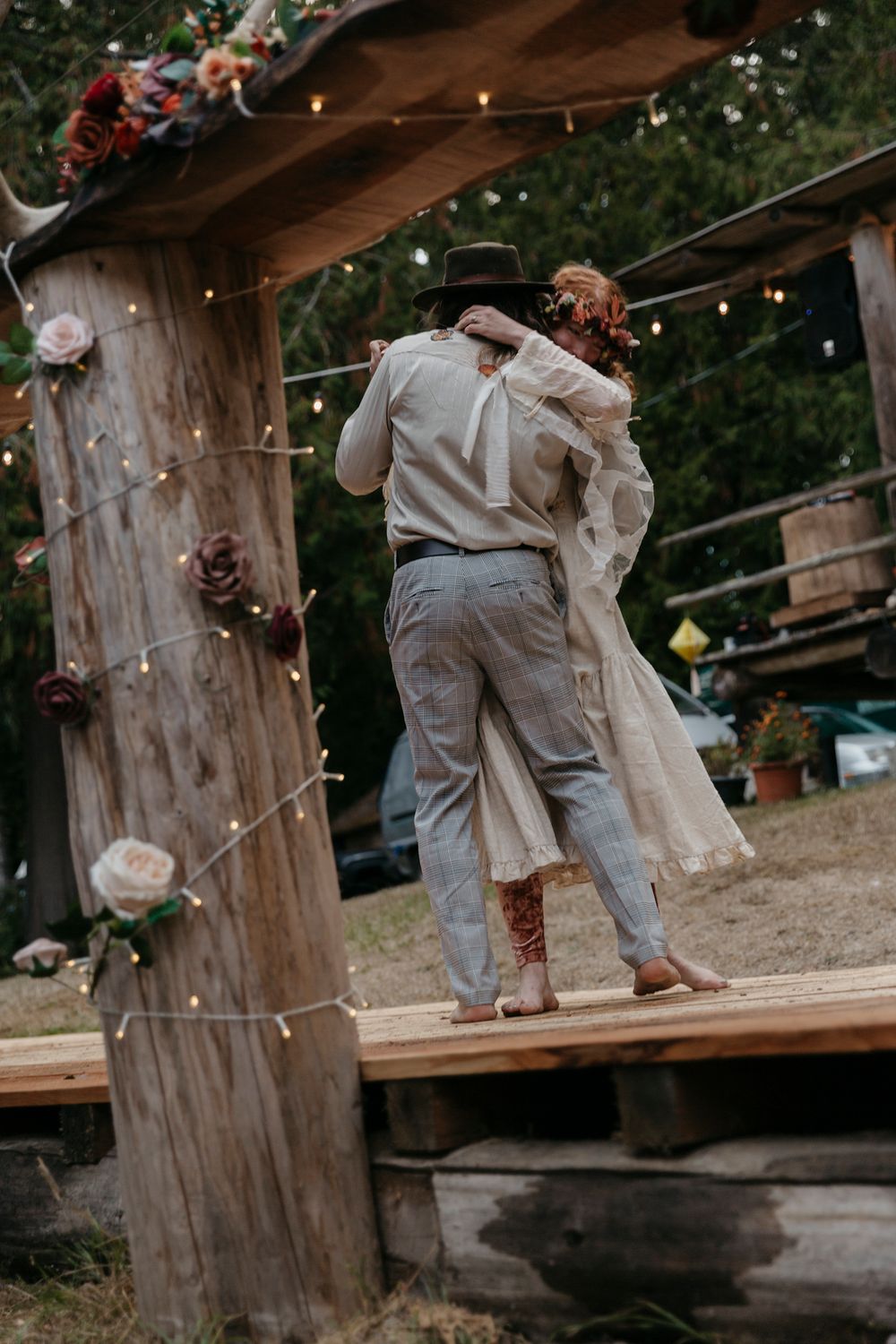 Outdoor celebration with vintage styled dancers performing together under rustic wooden beams and string lights.