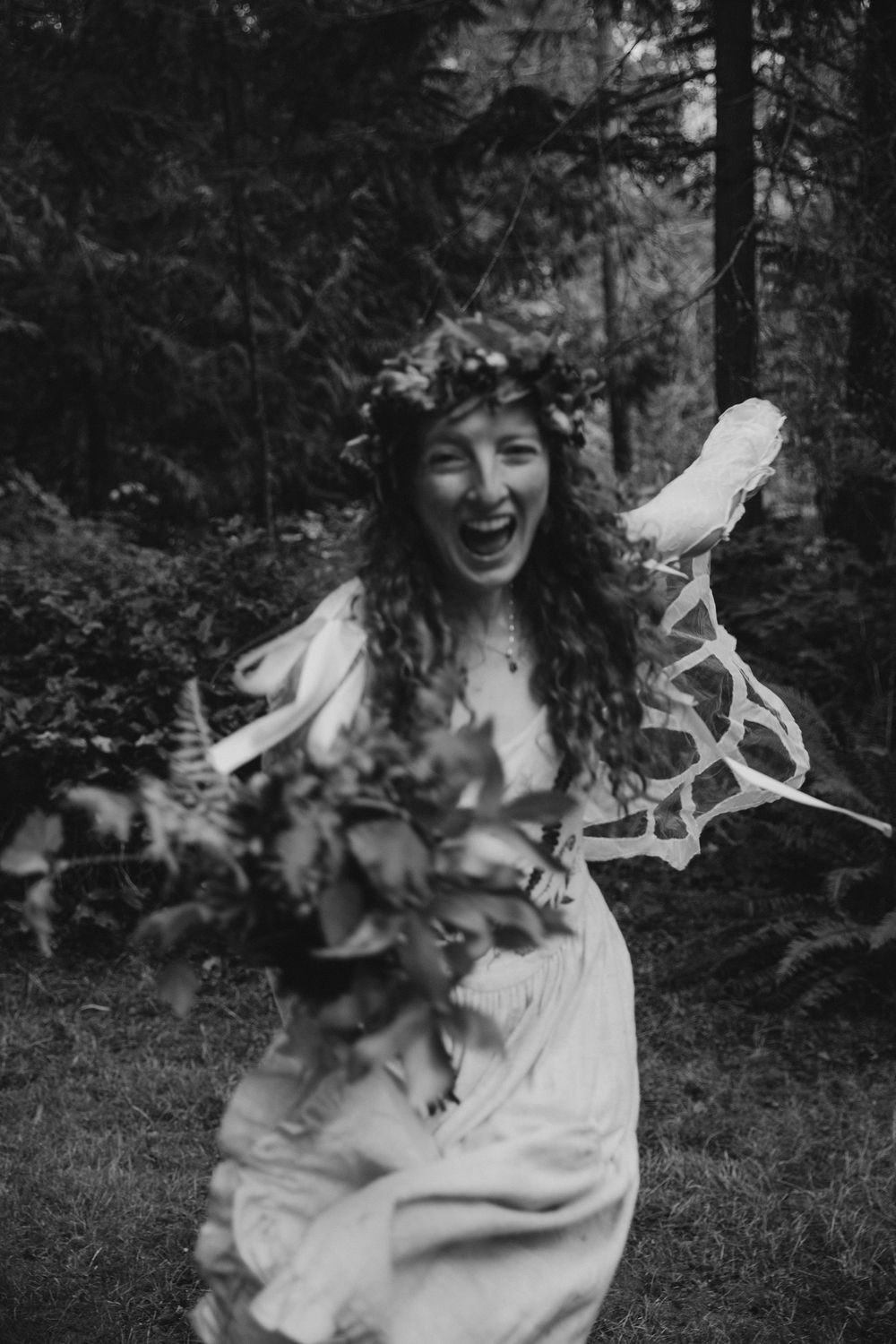 Joyful forest portrait with flowing dress and floral crown in black and white.
