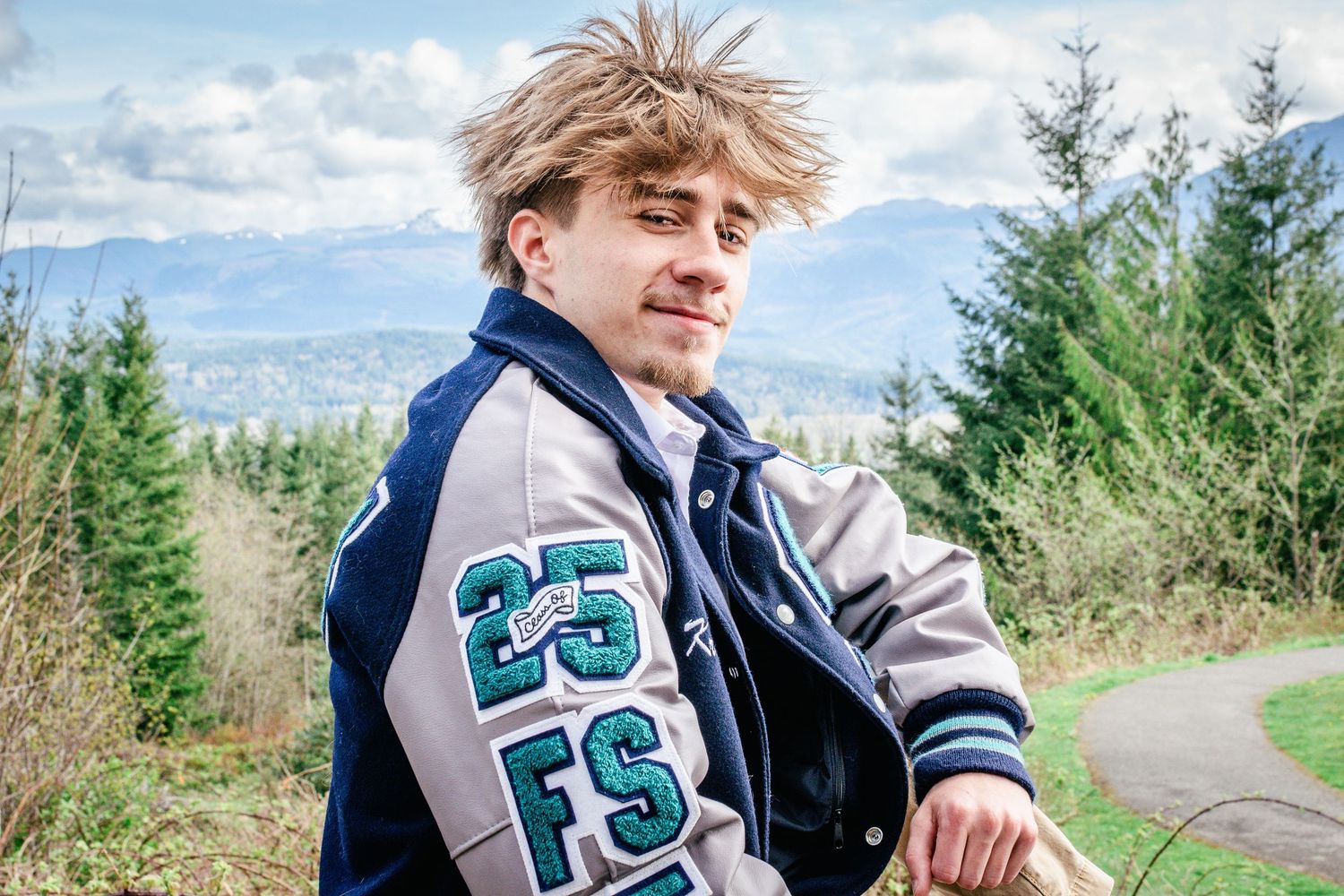Senior wearing a blue and gray letterman jacket during portrait session near Seattle.