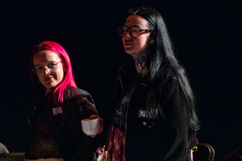 Four dramatic monochrome studio photos capturing a conversation in dark lighting with bright pink hair accent.