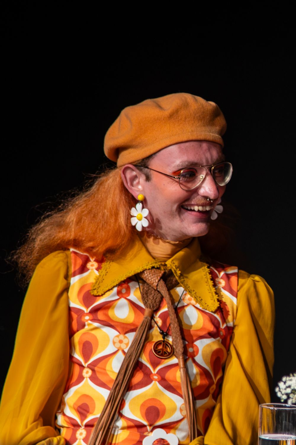 A series of photos showing someone in a yellow coat and orange beret playing a musical instrument against a dark background.