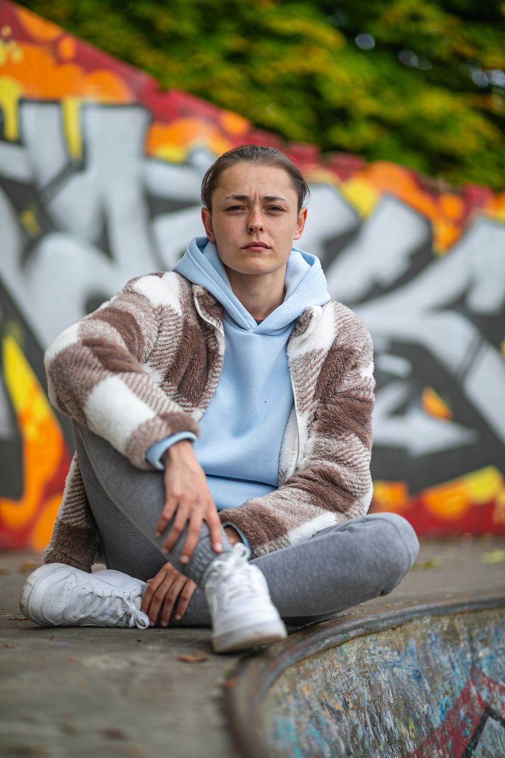 Casual portrait at a skate park with colorful graffiti in the background.