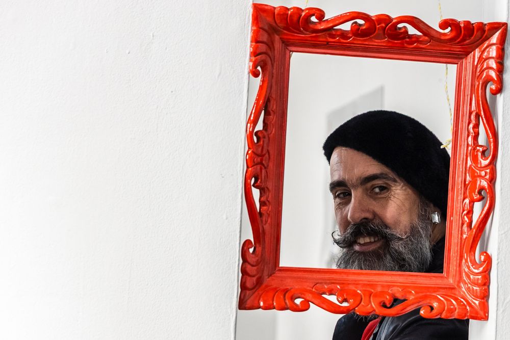 Four square red frames mounted on a white wall display artistic portraits in a gallery-style arrangement.