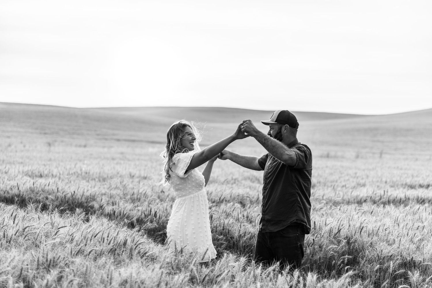 Couple dancing together in a wheat field, black and white romantic outdoor photo.