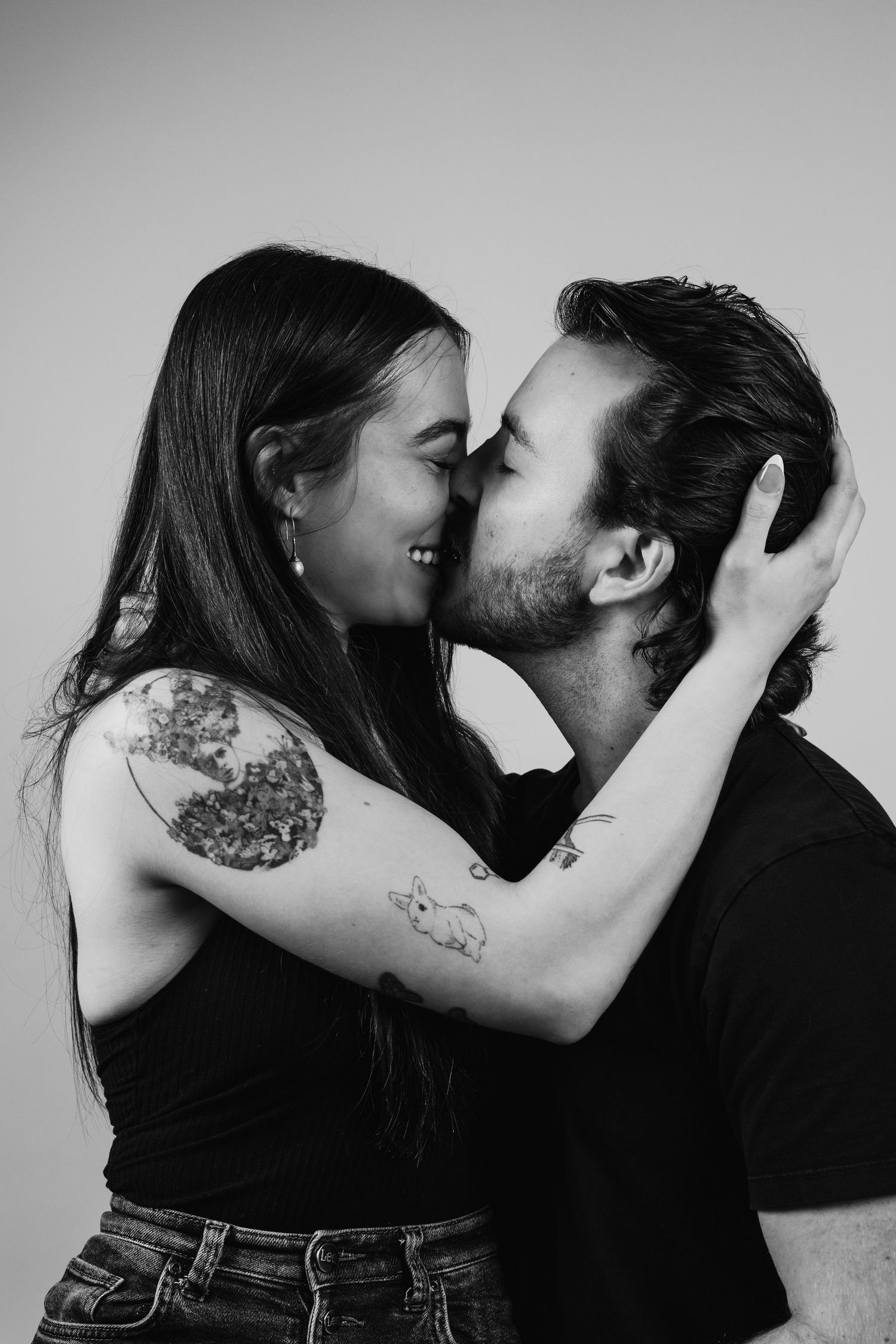 Black and white artistic photo series showing intimate romantic couple poses with visible tattoos against plain background.
