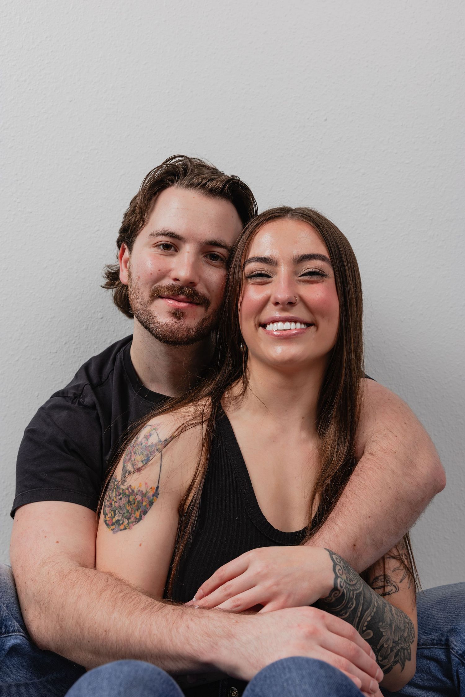 A couple poses together in a series of four playful photos showing affection against a gray background.