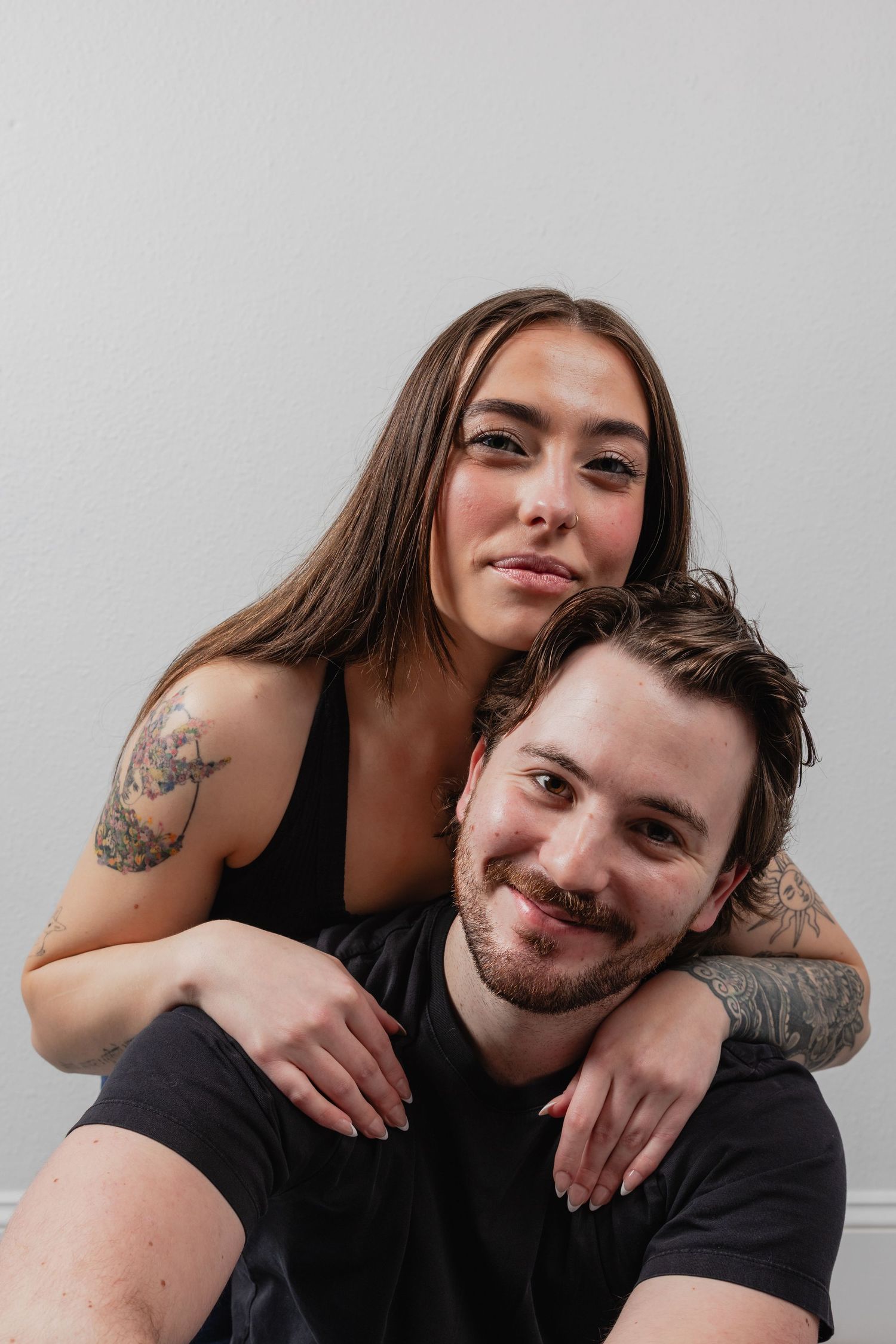 A couple in black shirts share playful and affectionate moments in a series of casual portrait photographs.