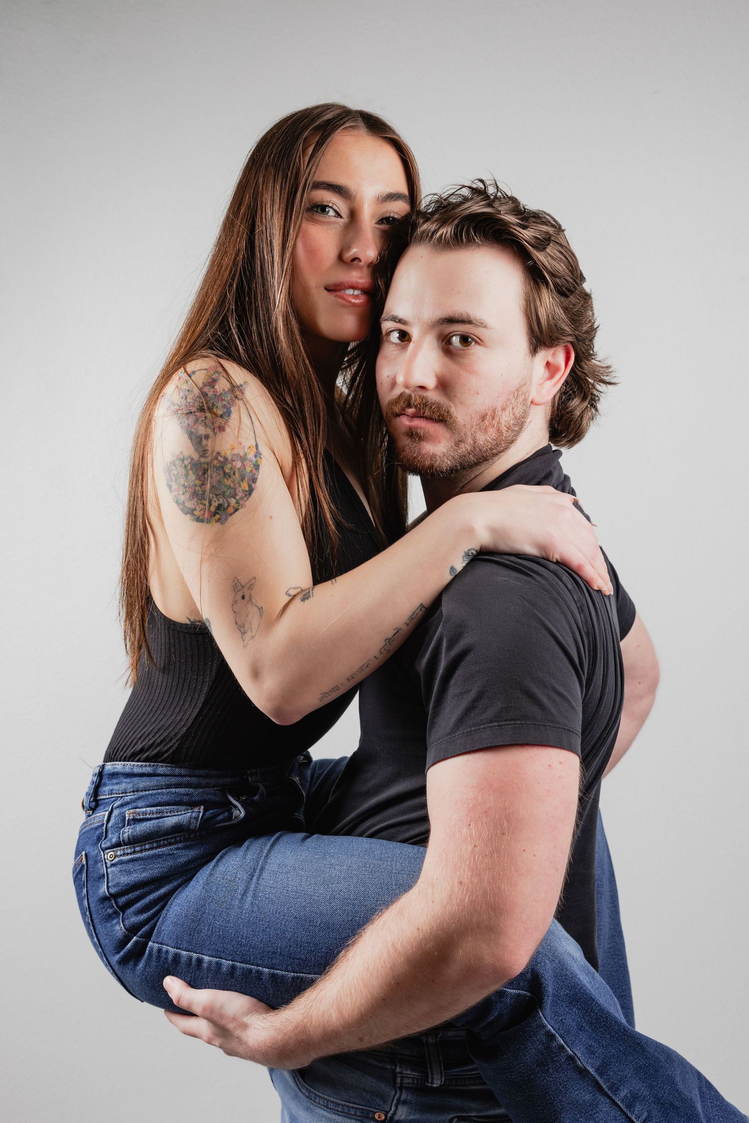 Candid photos of a couple in casual clothing sharing intimate moments against a light gray backdrop.