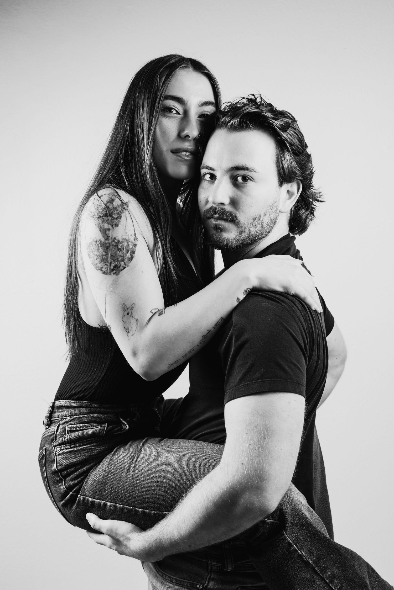 Black and white portrait series showing intimate couple poses against white background with artistic composition.