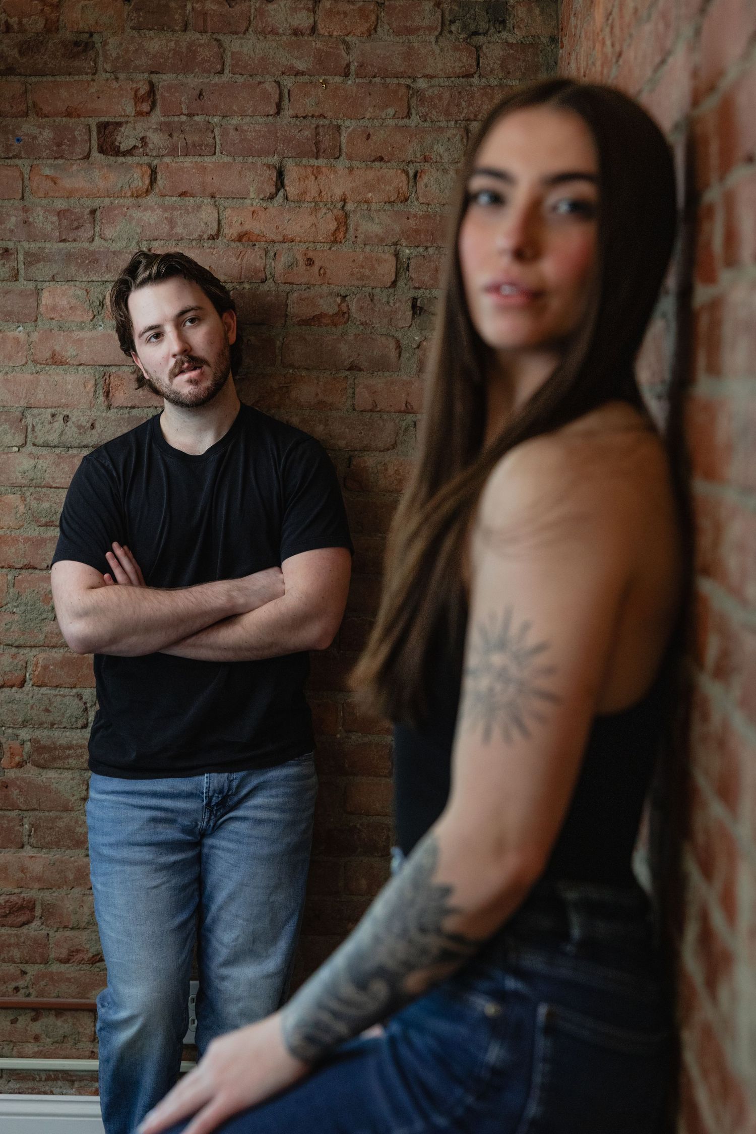 Couple posing against rustic brick wall in casual attire showing progressive intimate moments.