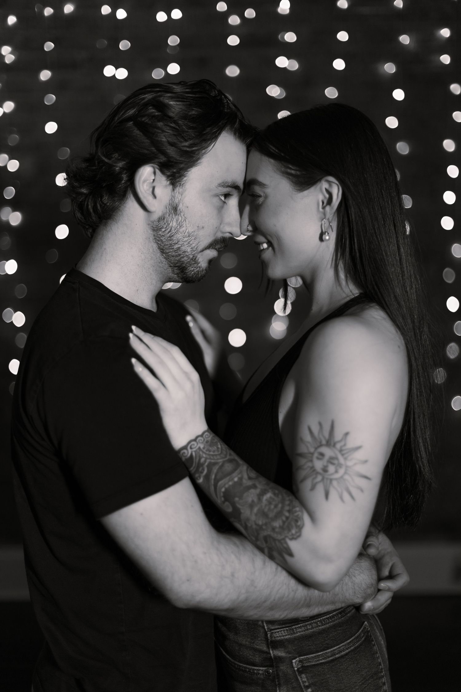 A romantic black and white photo series showing a couple embracing with twinkling lights in the background.