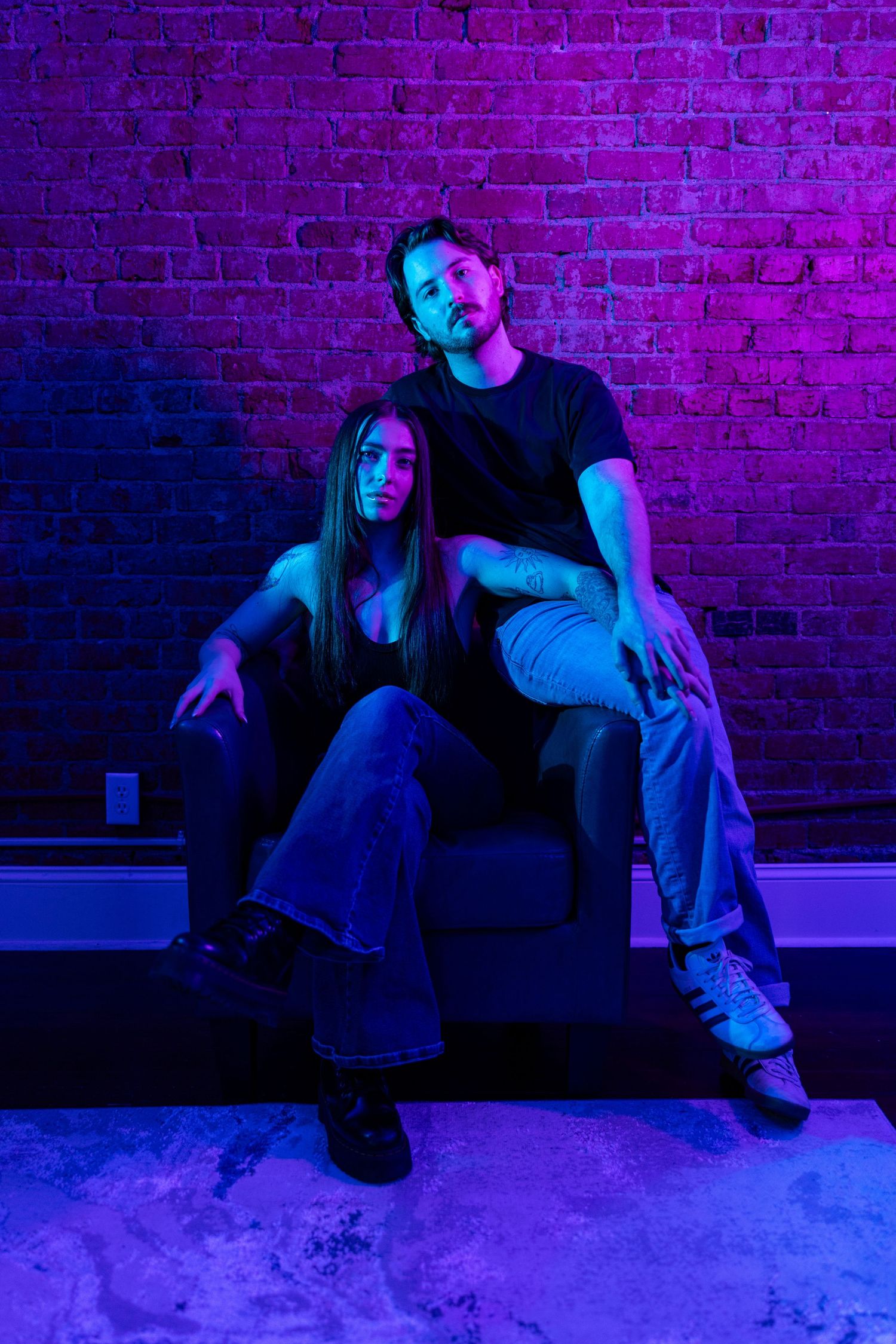 A person sits against a purple-lit brick wall in a moody artistic sequence showing different poses and movements.