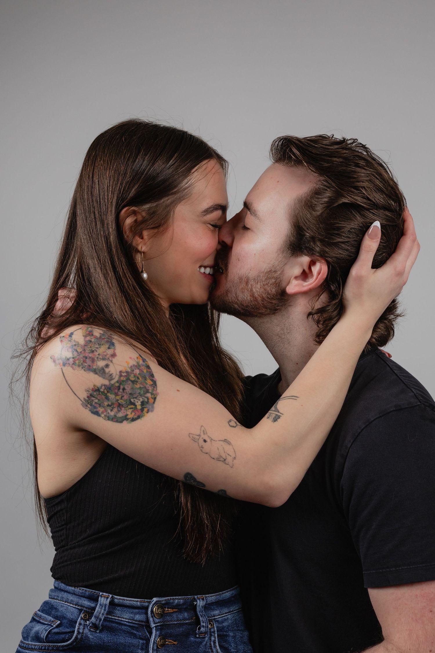 A couple shares intimate romantic moments in a series of black and white photographs against a studio backdrop.