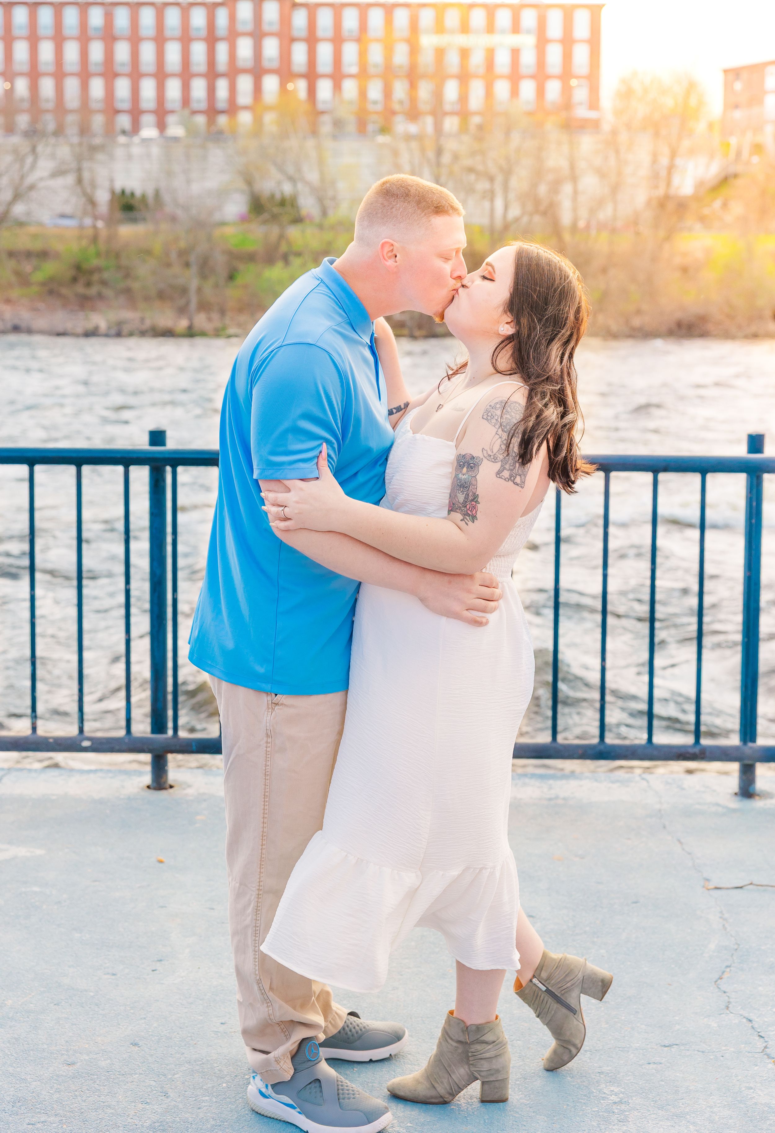 A romantic sunset moment by the water with industrial architecture in the background.