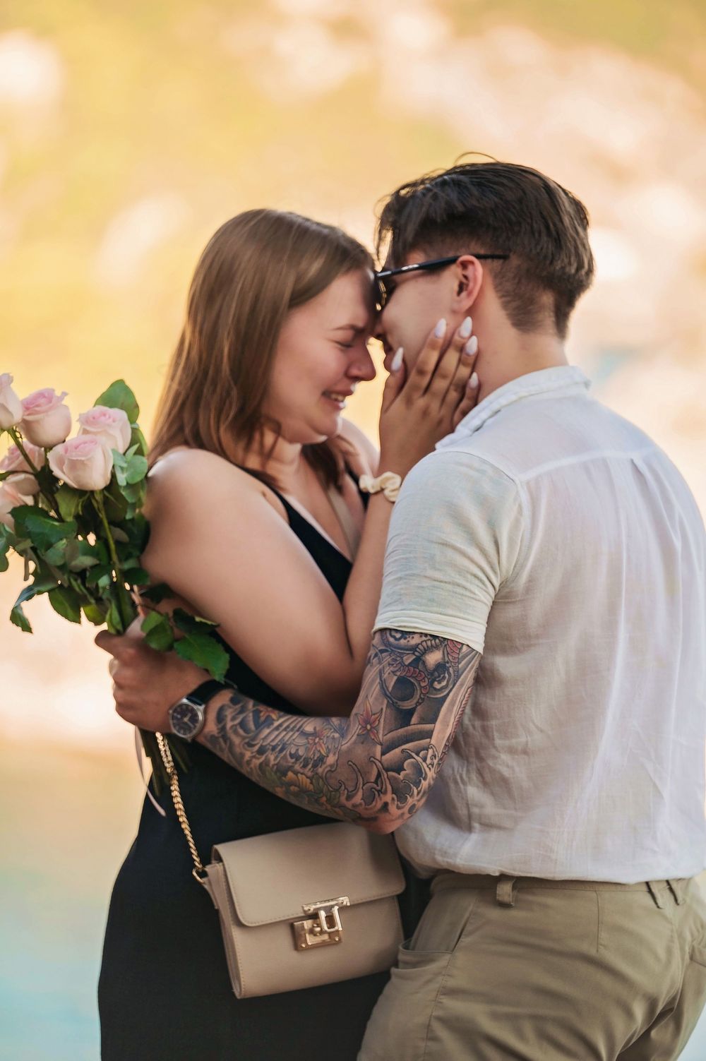 Intimate embrace after proposal with pink roses and Mediterranean Sea backdrop.