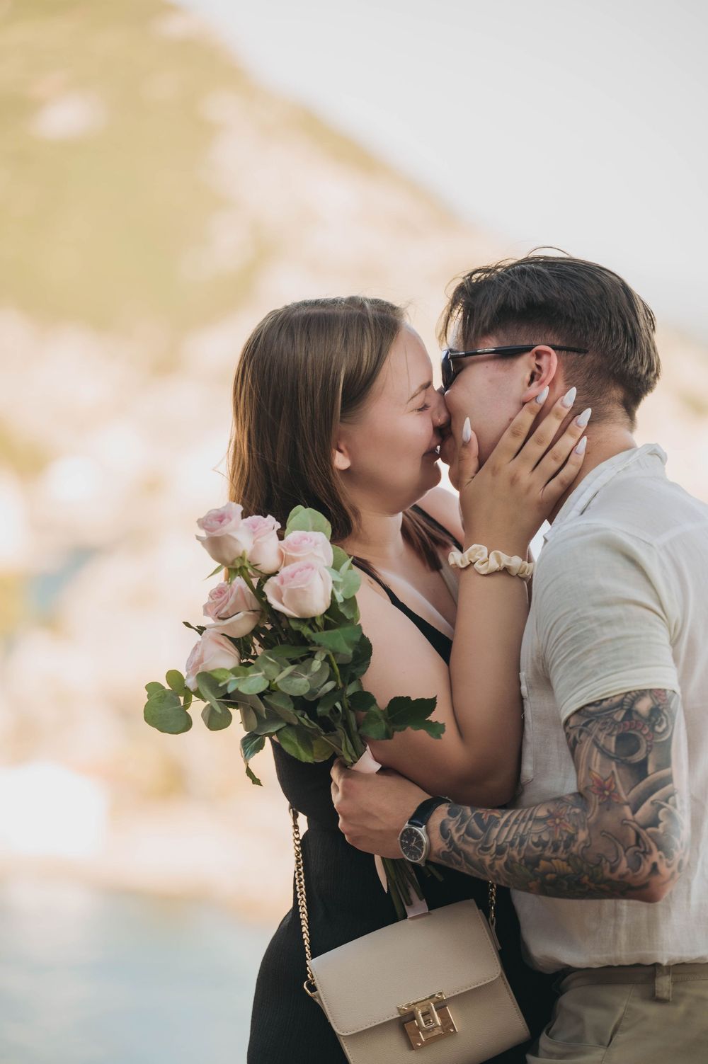 An emotional embrace captured during a romantic moment with pink roses and a designer purse.