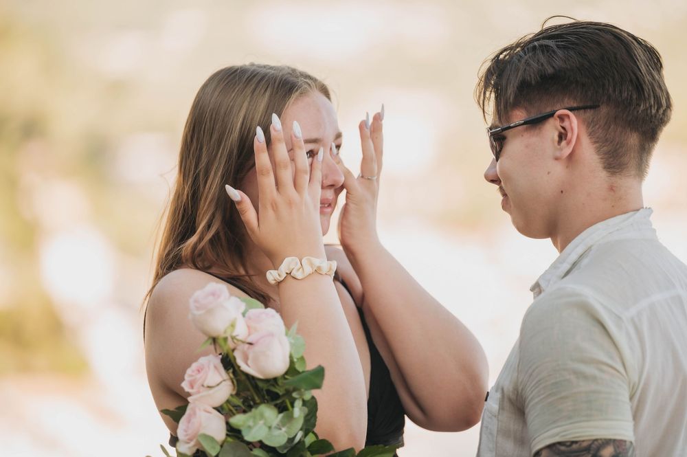 A joyful reaction during what appears to be a surprise proposal with pink roses.