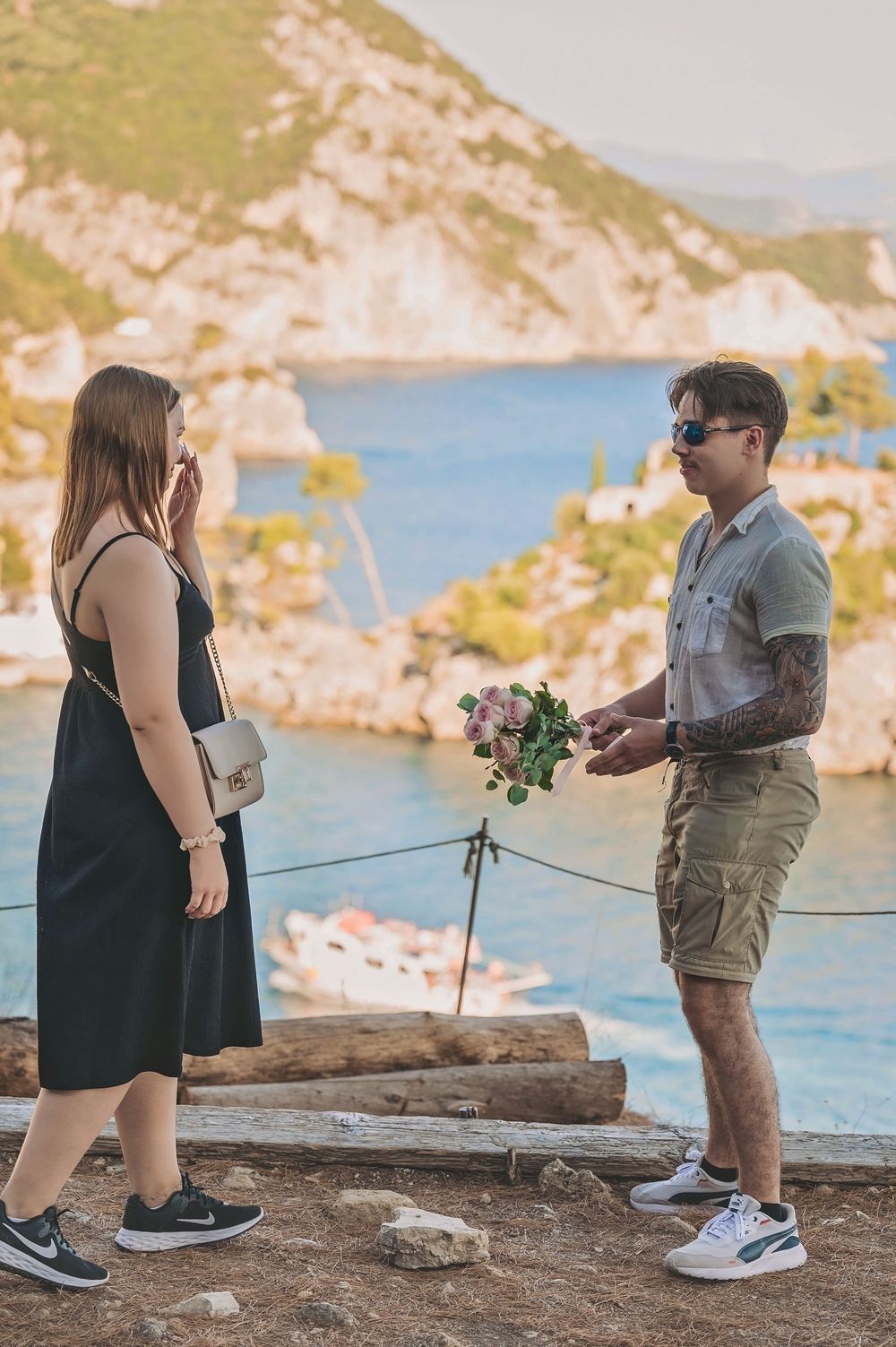 Couple sharing a special moment on a coastal cliff overlook with blue waters in background.