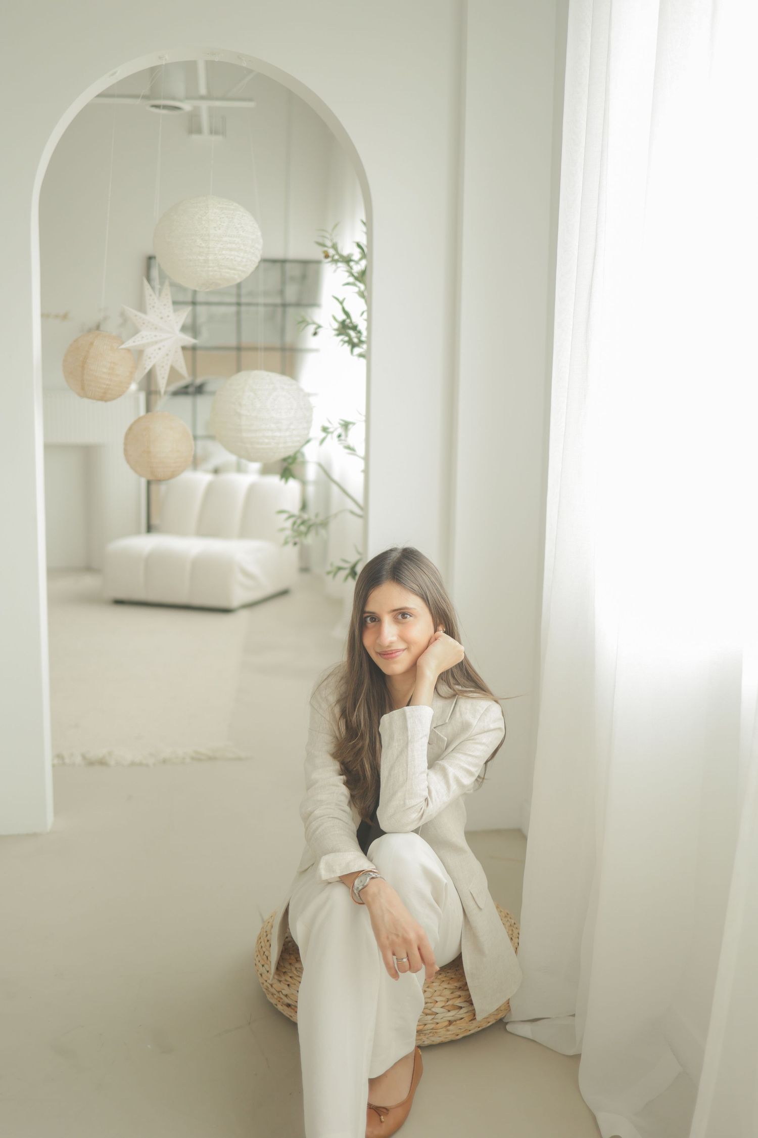Dreamy indoor portraits in white dress against minimalist arched room with paper lanterns.