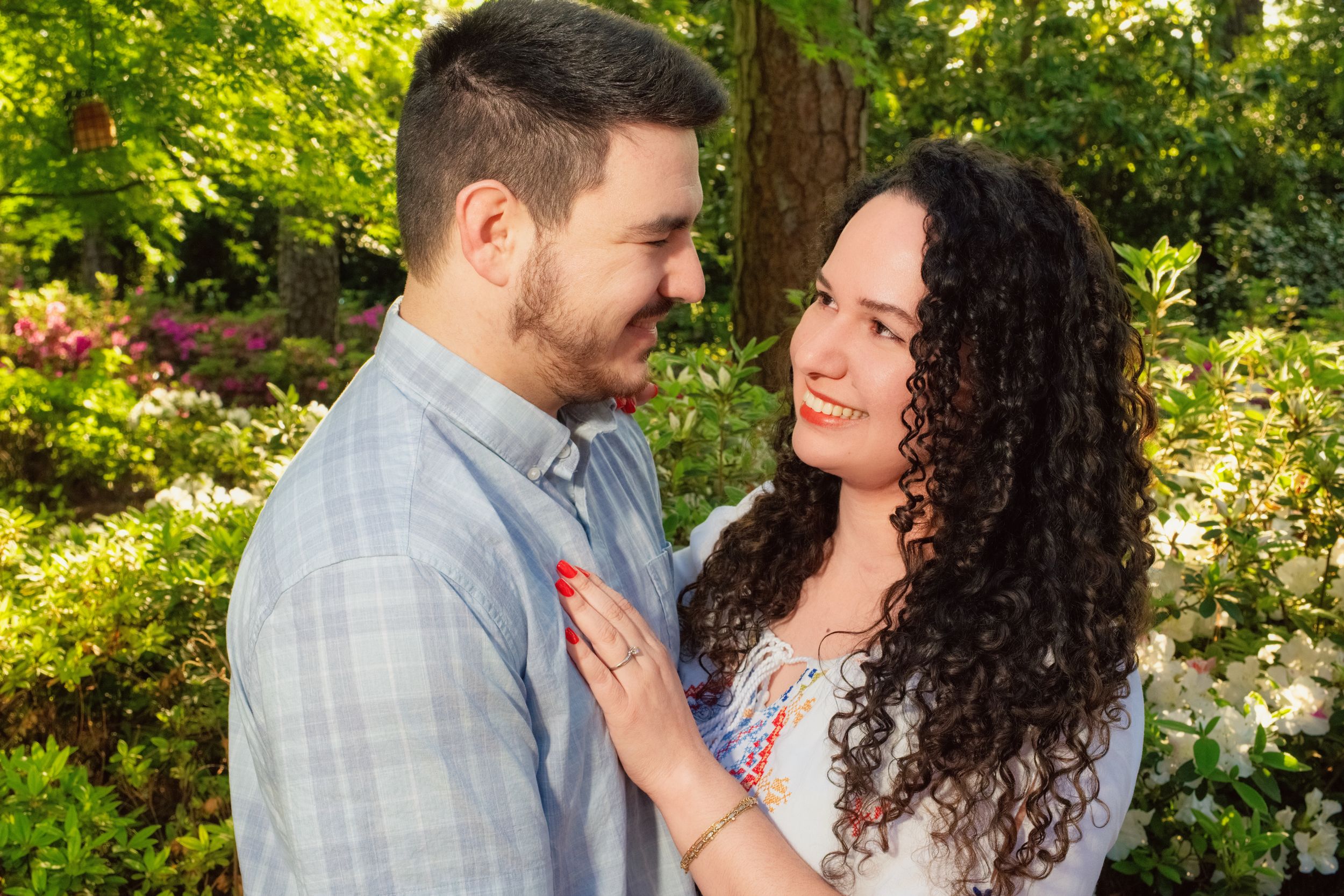 Romantic couple sharing an intimate moment in a sunlit garden setting surrounded by greenery.