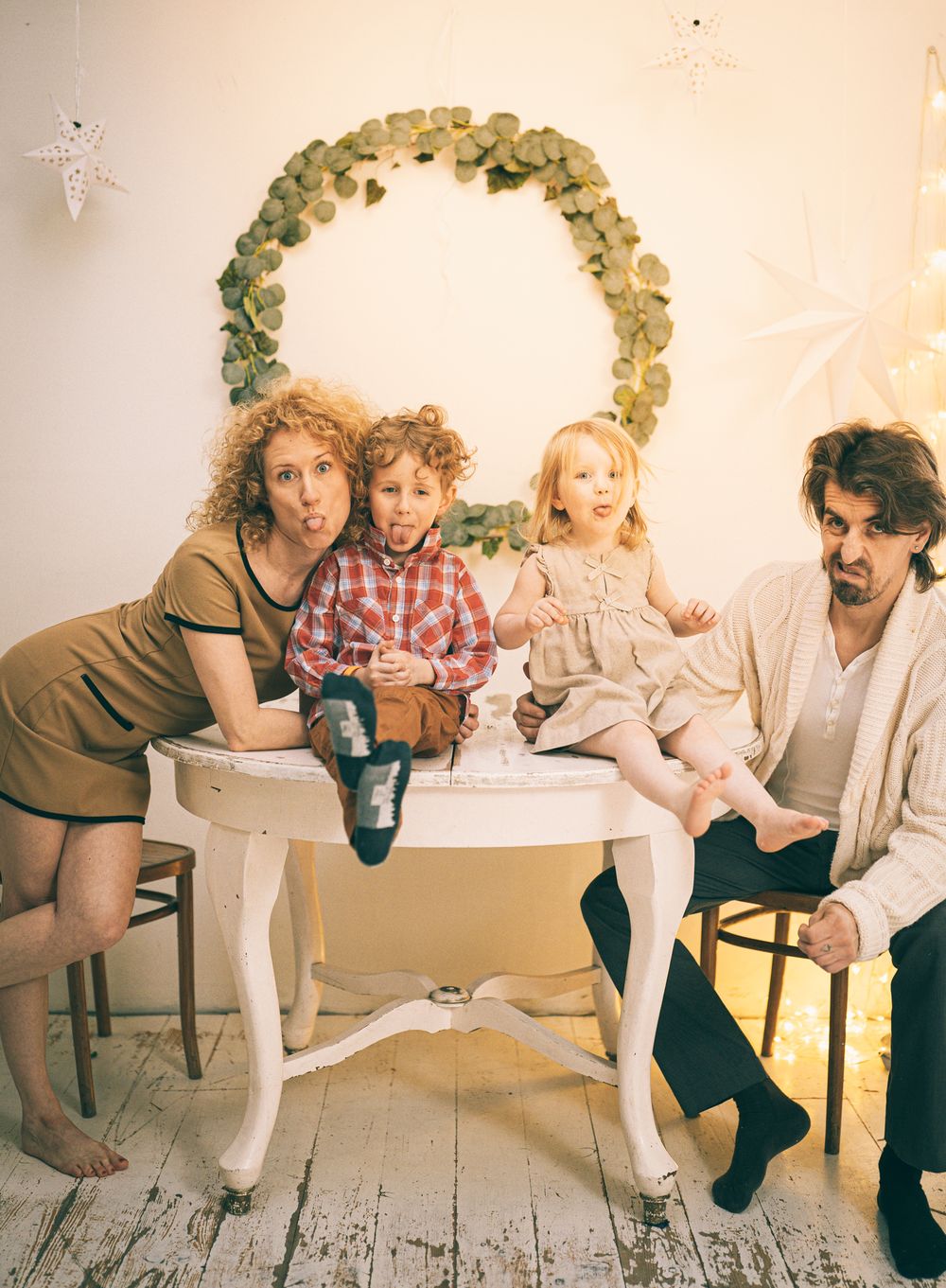 Family photo with people seated at a white table under a decorative green and gold arch.