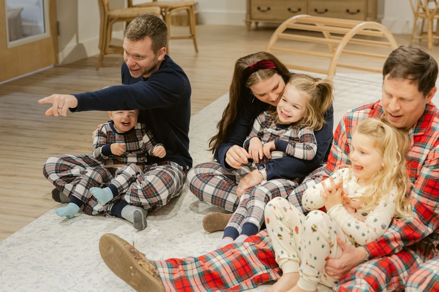 Chattanooga family wearing matching plaid christmas pajamas sits together on floor during cozy holiday gathering at the bunny hive.